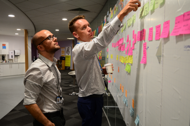 Two colleagues working together at a stand up wall 